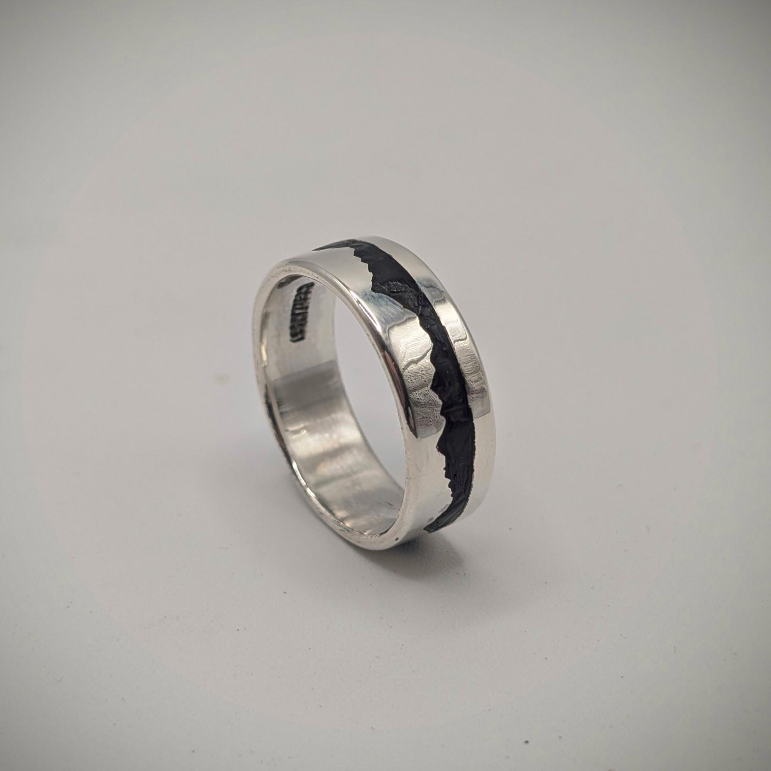 Silver ring with a black interior on a gray background
