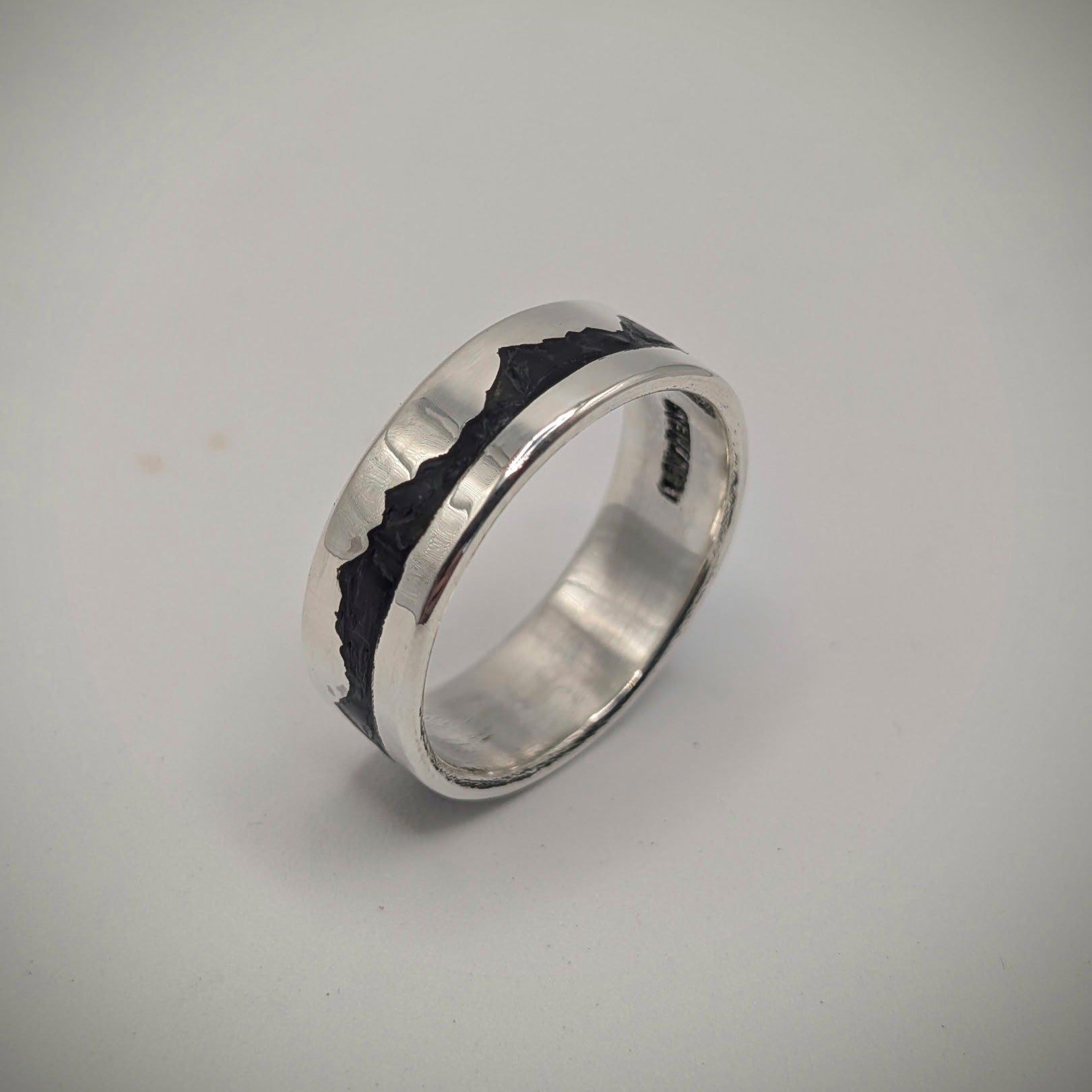 Silver ring with black interior on a light gray background