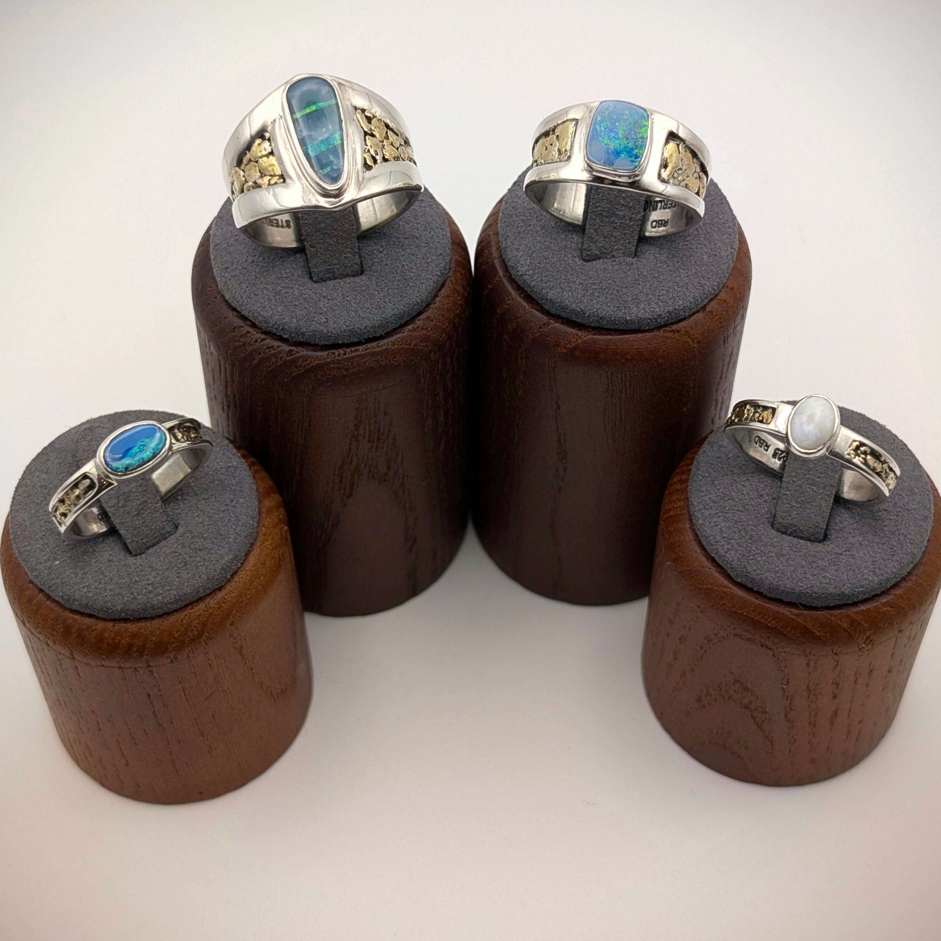 Four wooden ring stands with rings on a white background