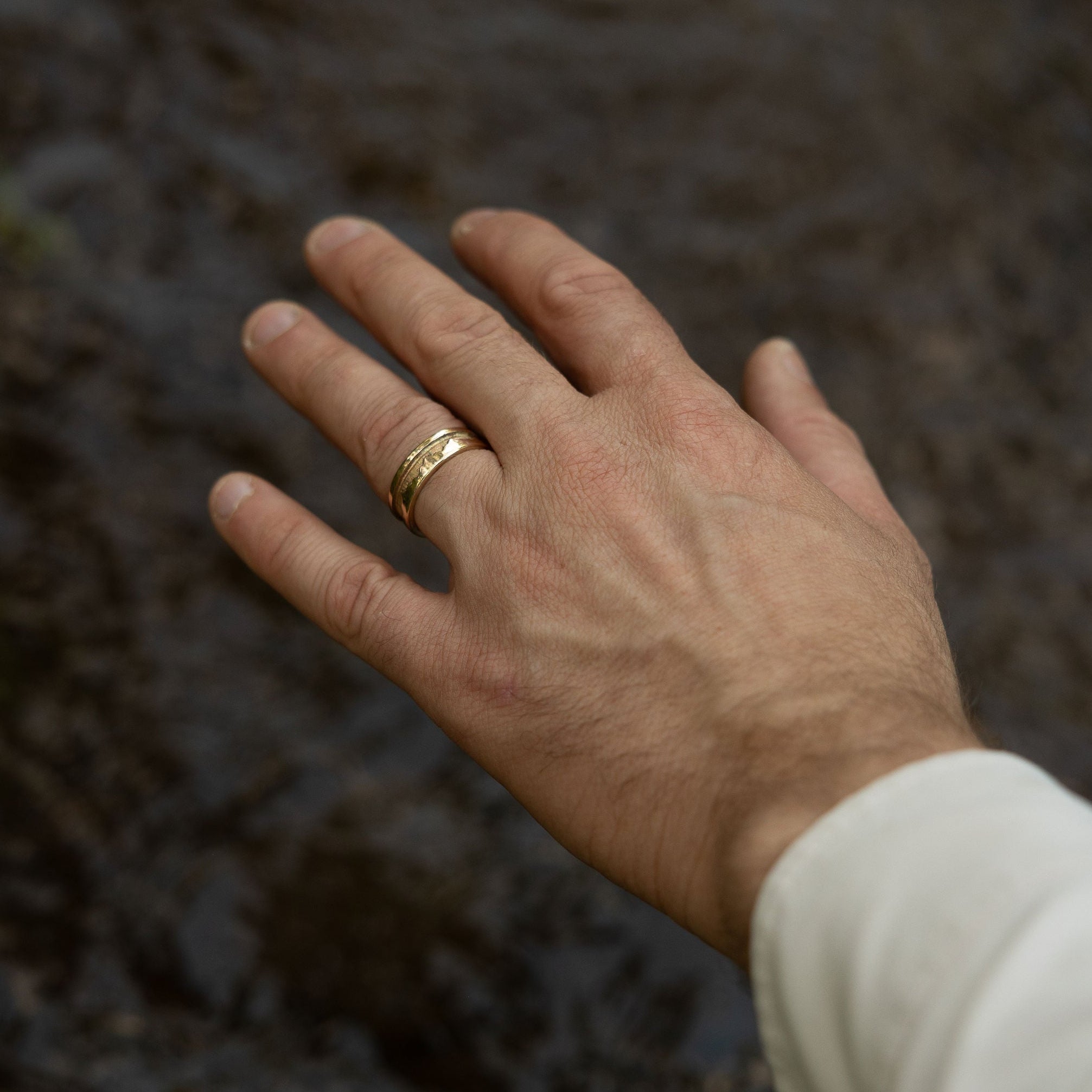 Hand with a gold ring on a blurred natural background