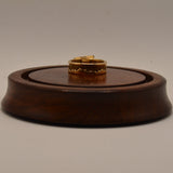 Gold ring on a wooden display stand against a plain background
