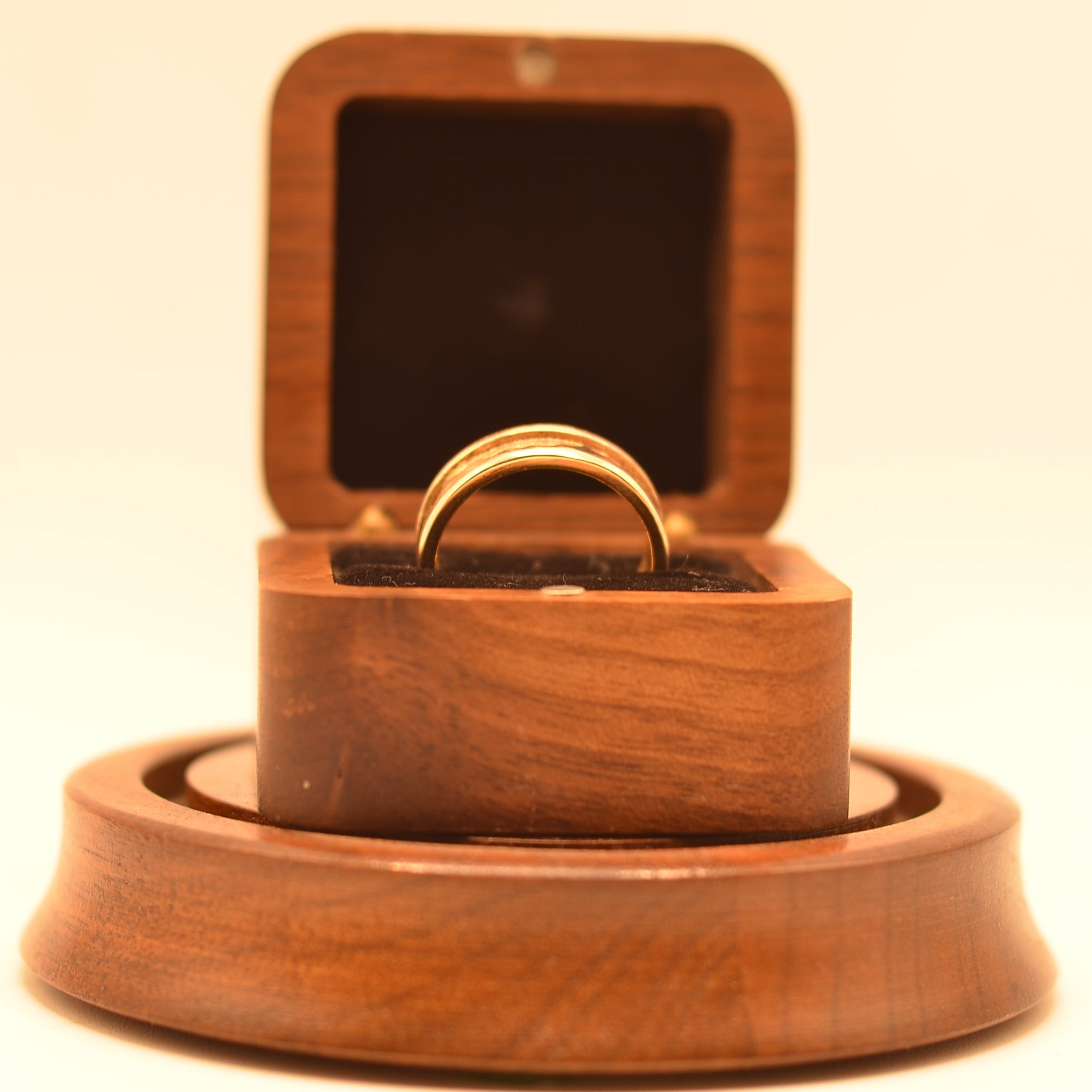 Wooden ring box with a ring inside on a beige background