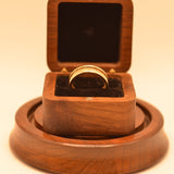 Wooden ring box with a gold ring on a beige background