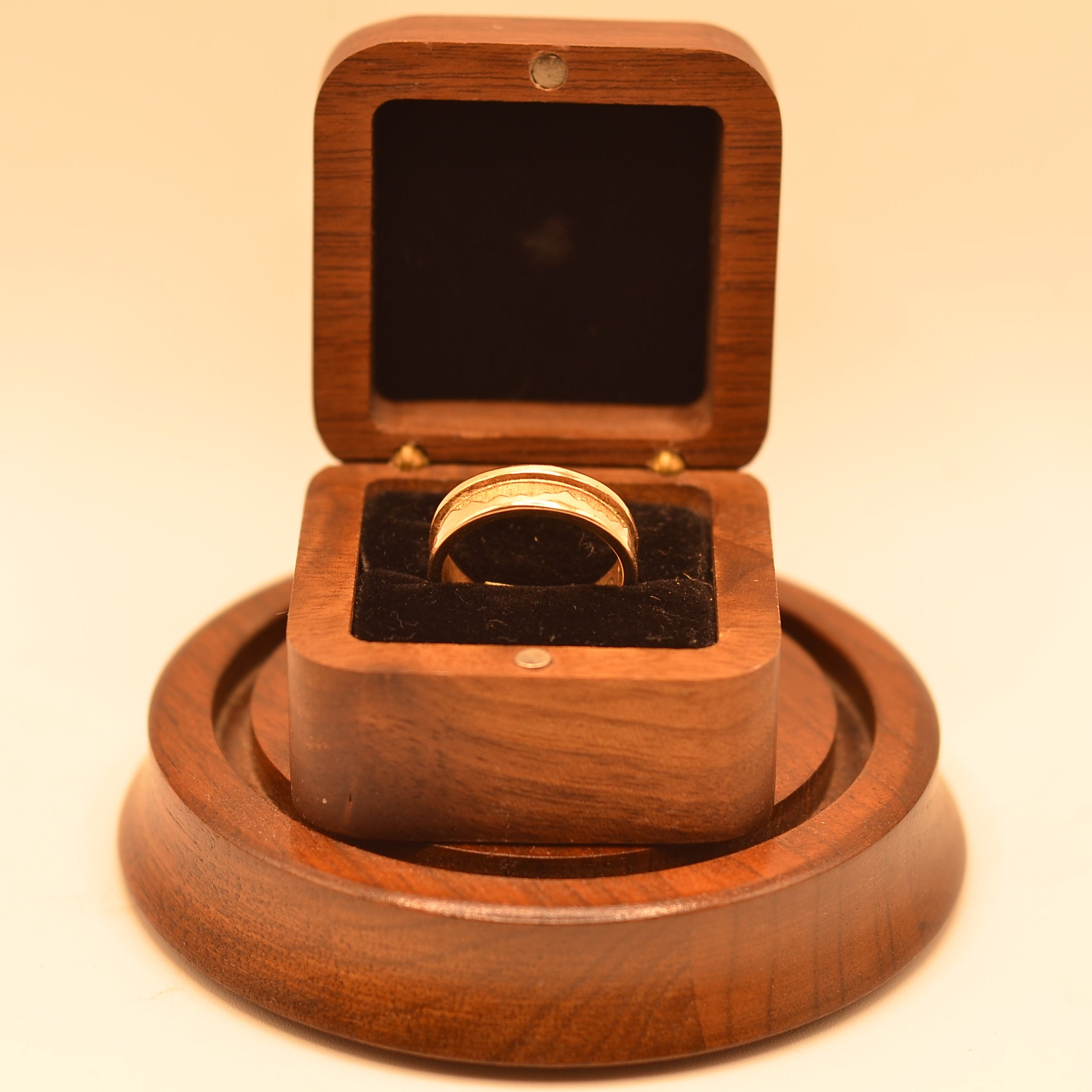 Wooden ring box with a ring inside on a matching wooden stand.