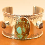 Silver cuff bracelet with a central turquoise stone on an leather surface