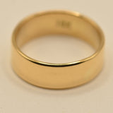 A classic yellow gold band ring with a smooth, polished finish, photographed on a plain light beige background.