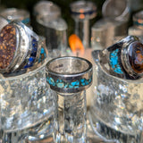 Close-up of silver rings with gemstones on a reflective surface