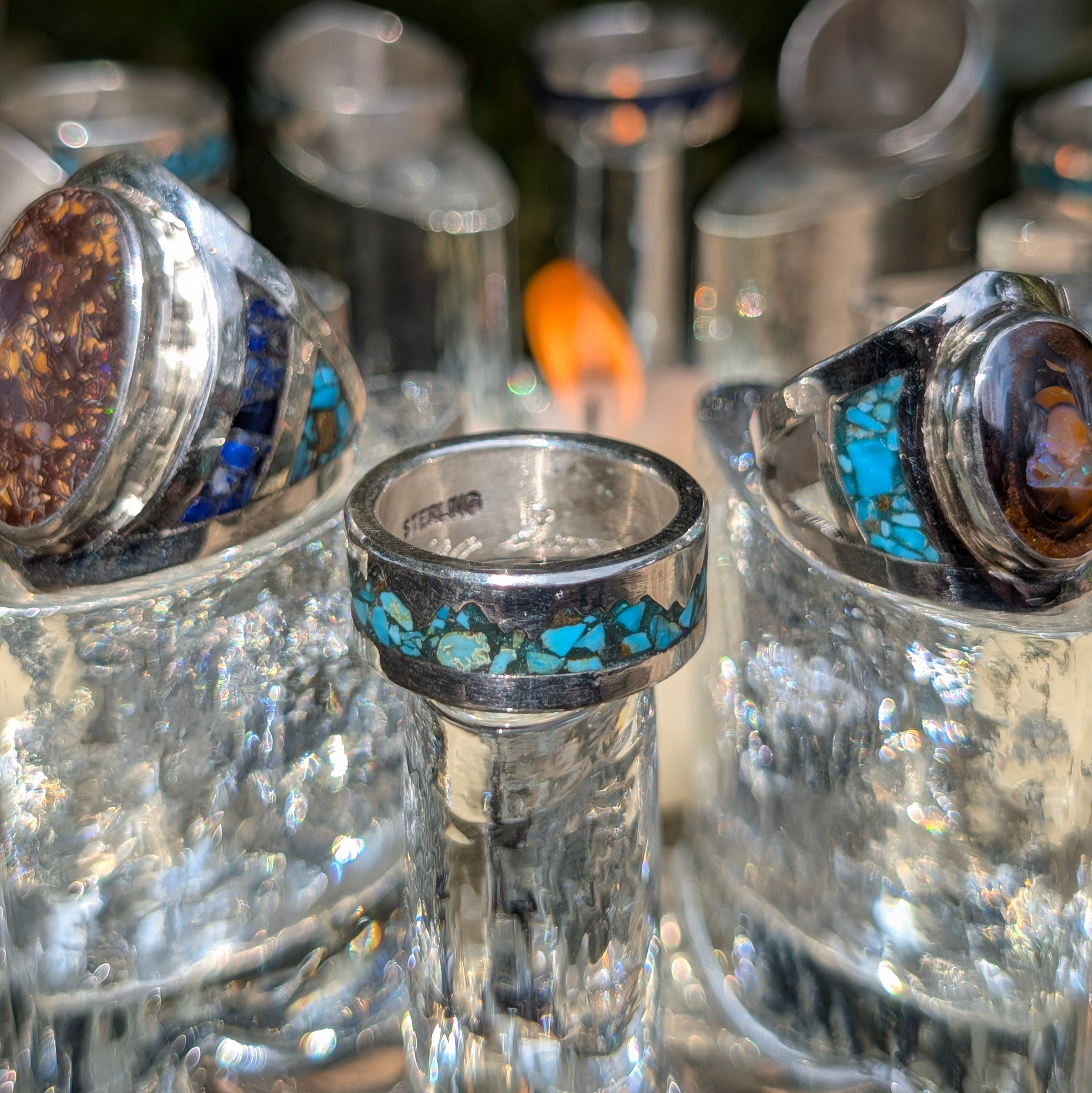 Close-up of silver rings with gemstones on a reflective surface