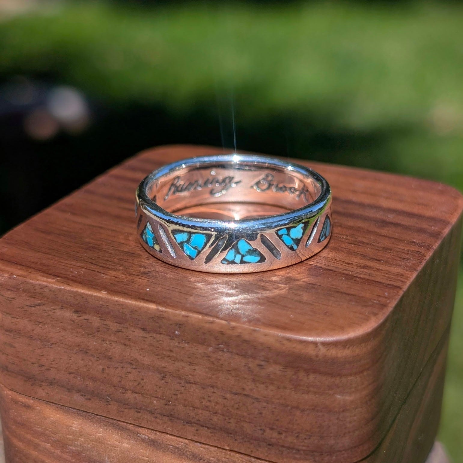 Silver ring with turquoise stones on a wooden box outdoors