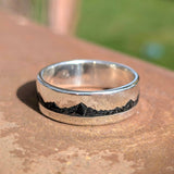 Sterling silver ring with onyx stone inlay on stone surface