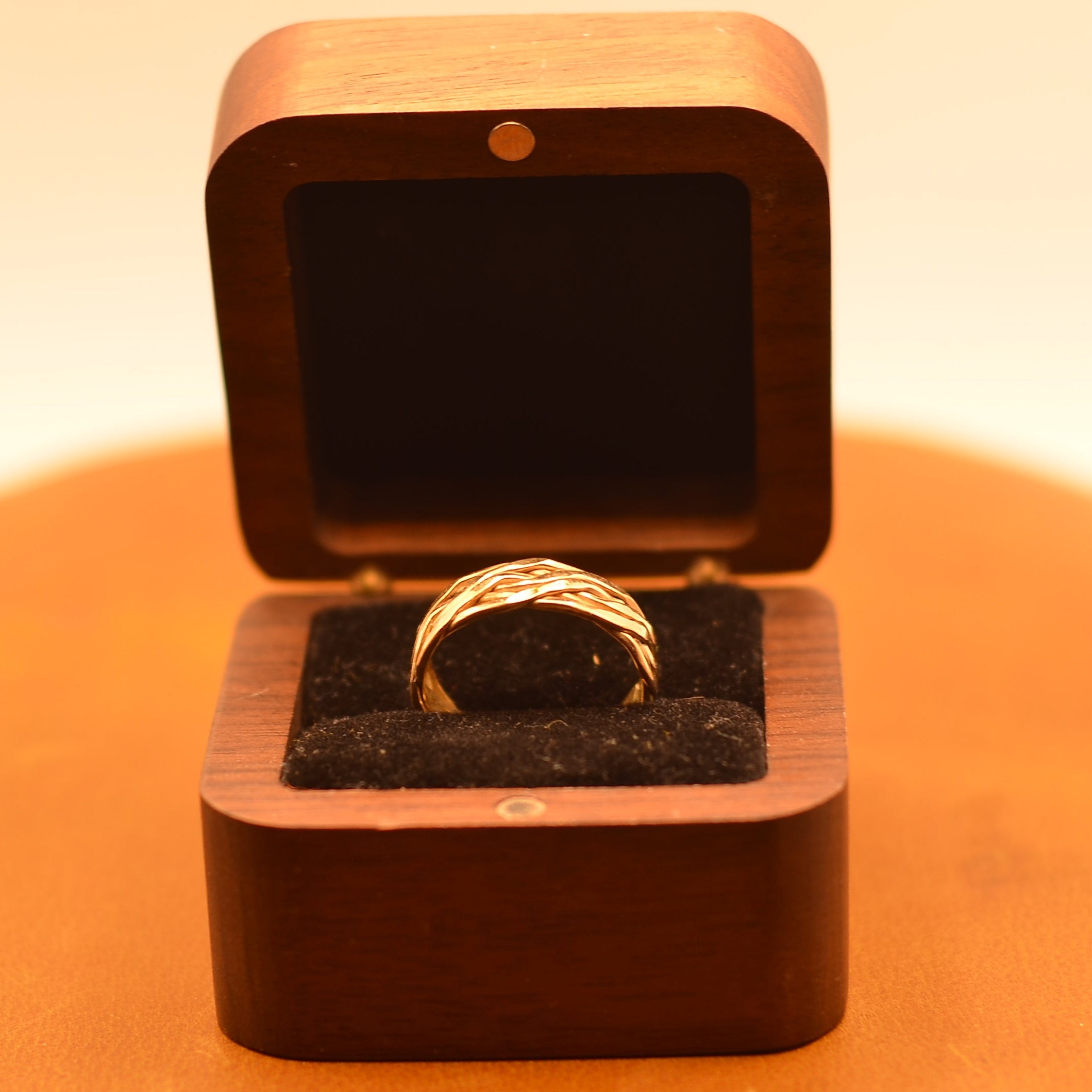 Gold ring in a wooden box on a warm-toned background
